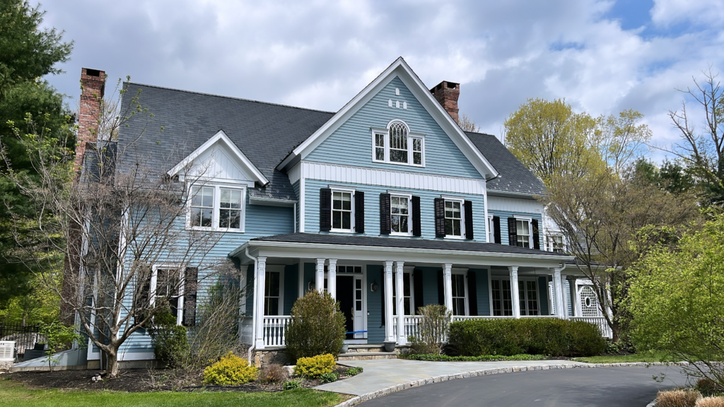Exterior house painting project in Ridgefield CT with light blue siding and dark shutters